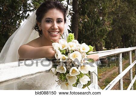 Hispanic bride with bouquet leaning on railing View Large Photo Image Stock Image - Hispanic bride with bouquet leaning on railing. Fotosearch