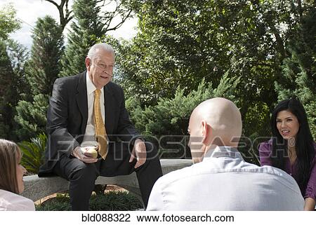 Stock Image - Hispanic business people talking together outdoors. Fotosearch