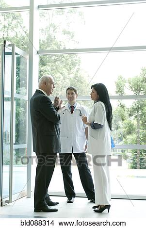 Picture - Hispanic business people talking to doctor in lobby. Fotosearch