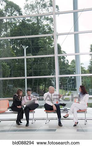 Picture - Hispanic business people working together in lobby. Fotosearch