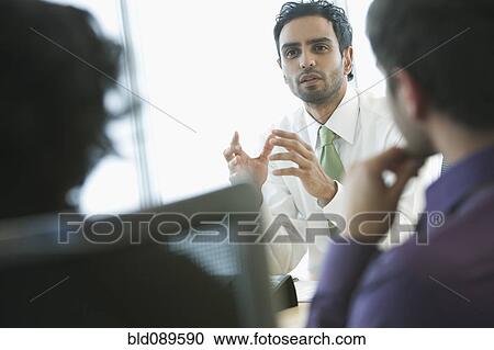 Stock Image - Hispanic business people working together in office. Fotosearch