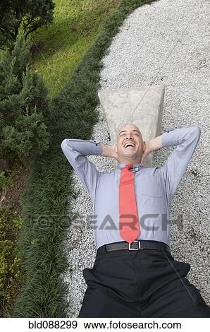 Stock Photo - Hispanic businessman laying on bench outdoors. Fotosearch