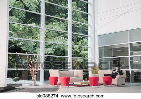 Picture - Hispanic businessman sitting on sofa waiting. Fotosearch