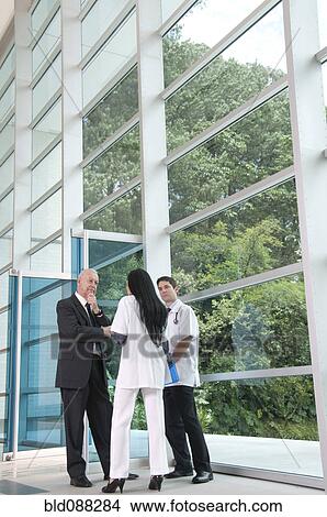 Hispanic businessman talking to doctor in lobby View Large Photo Image Picture - Hispanic businessman talking to doctor in lobby. Fotosearch