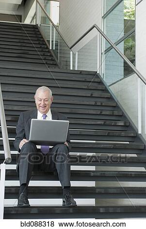 Stock Photo - Hispanic businessman using laptop on staircase. Fotosearch