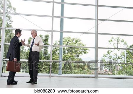 Stock Image - Hispanic businessmen talking together in lobby. Fotosearch