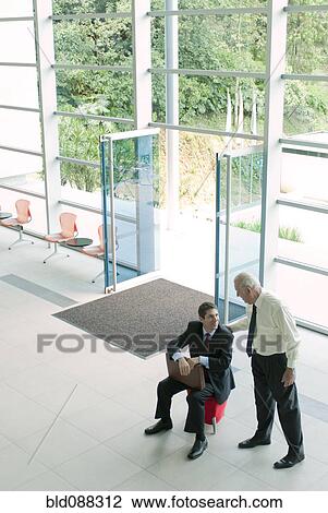 Stock Image - Hispanic businessmen talking together in lobby. Fotosearch