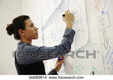 Picture - Hispanic businesswoman drawing on paper in office. Fotosearch