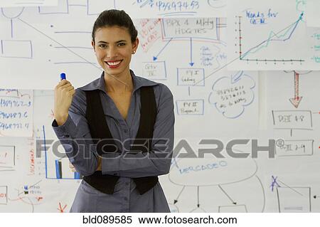 Stock Photography - Hispanic businesswoman standing near drawings on whiteboard. Fotosearch