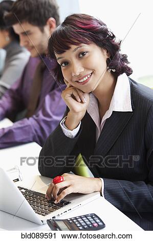 Stock Image - Hispanic businesswoman working on laptop in office. Fotosearch