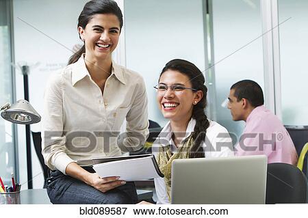 Stock Photo - Hispanic businesswomen working together in office. Fotosearch