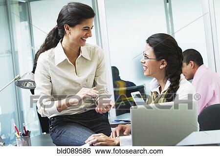 Hispanic businesswomen working together in office View Large Photo Image Stock Photograph - Hispanic businesswomen working together in office. Fotosearch