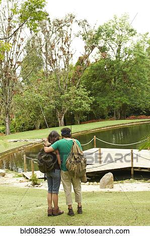 Stock Photograph - Hispanic couple hugging near pier on lake. Fotosearch