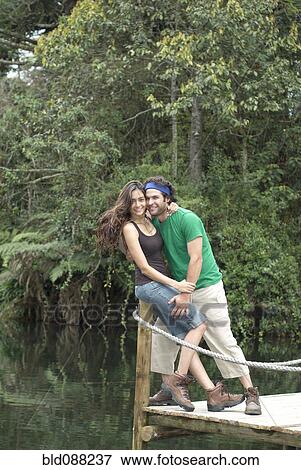 Stock Photo - Hispanic couple hugging on pier. Fotosearch
