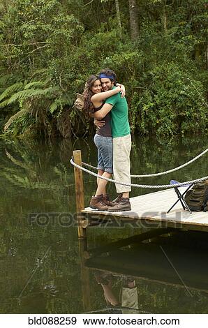 Stock Photo - Hispanic couple hugging on pier. Fotosearch
