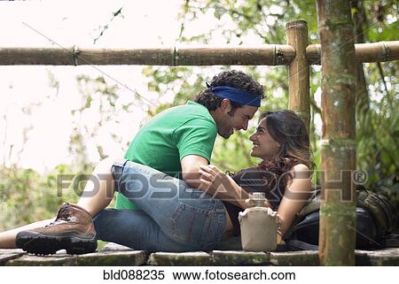 Stock Photography - Hispanic couple relaxing together on wooden walkway. Fotosearch