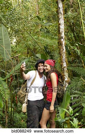 Stock Photo - Hispanic couple talking self-portrait in forest. Fotosearch