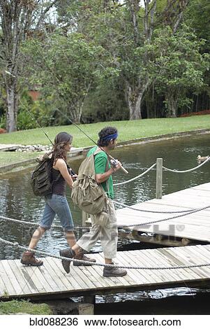 Hispanic couple walking on pier carrying fishing poles View Large Photo Image Stock Photograph - Hispanic couple walking on pier carrying fishing poles. Fotosearch