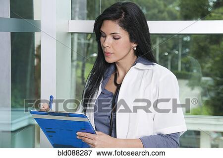 Stock Photo - Hispanic doctor writing in medical chart. Fotosearch