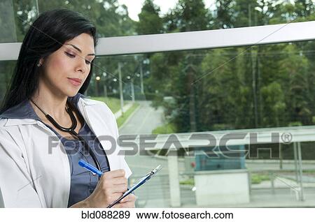 Hispanic doctor writing in medical chart View Large Photo Image Stock Photo - Hispanic doctor writing in medical chart. Fotosearch