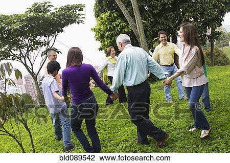 Stock Image - Hispanic family holding hands in a circle outdoors. Fotosearch