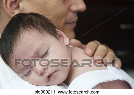 Stock Image - Hispanic father cuddling baby daughter. Fotosearch