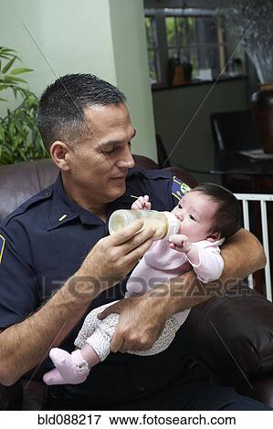 Stock Photo - Hispanic father feeding baby daughter. Fotosearch