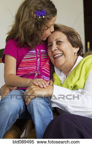 Stock Photography - Hispanic granddaughter kissing grandmother. Fotosearch