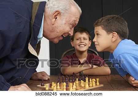 Stock Photography - Hispanic grandfather and grandsons playing chess. Fotosearch