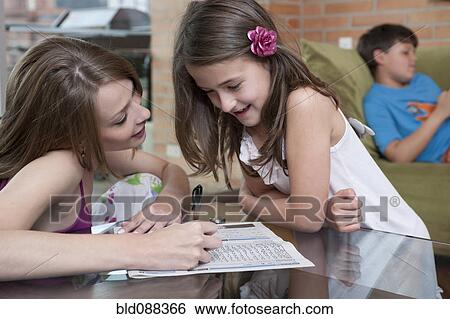 Stock Photograph - Hispanic mother and daughter looking at word puzzle. Fotosearch