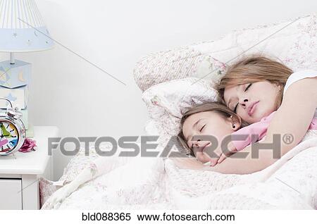 Stock Photography - Hispanic mother and daughter sleeping together in bed. Fotosearch