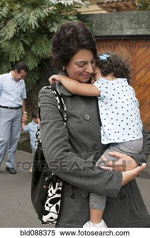 Stock Photography - Hispanic mother carrying daughter. Fotosearch