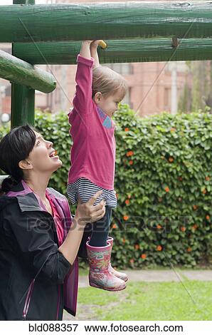 Hispanic mother helping daughter in playground View Large Photo Image Stock Photo - Hispanic mother helping daughter in playground. Fotosearch