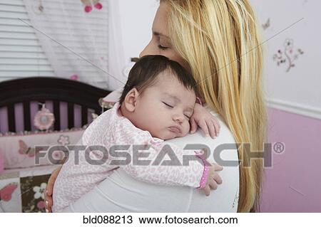 Stock Image - Hispanic mother holding baby daughter. Fotosearch
