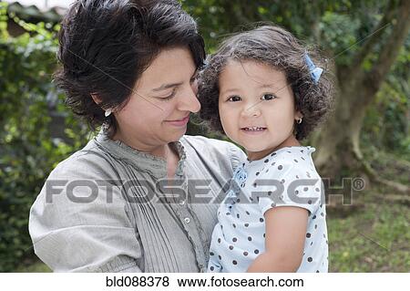 Stock Photo - Hispanic mother holding daughter outdoors. Fotosearch
