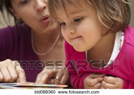 Hispanic mother reading book to daughter View Large Photo Image Stock Image - Hispanic mother reading book to daughter. Fotosearch