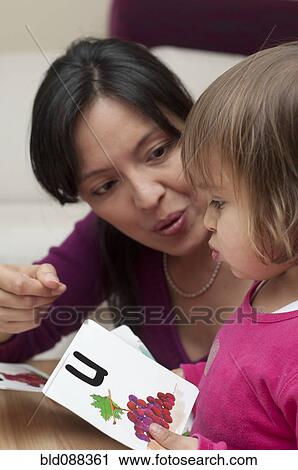 Stock Image - Hispanic mother teaching daughter alphabet. Fotosearch