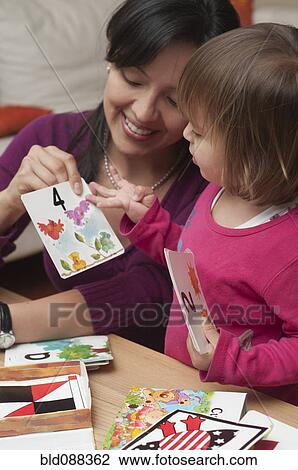 Stock Image - Hispanic mother teaching daughter numbers. Fotosearch