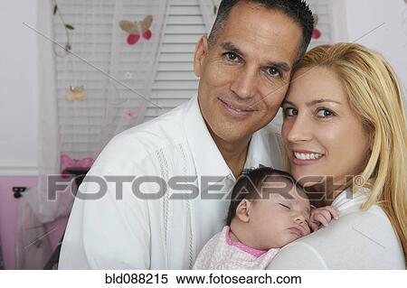 Stock Photography - Hispanic parents holding baby daughter. Fotosearch