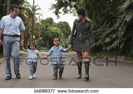 Stock Photo - Hispanic parents holding children's hands outdoors. Fotosearch