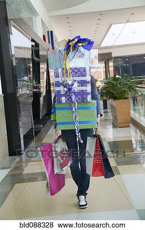 Stock Photo - Hispanic teenager carrying gifts in shopping mall. Fotosearch
