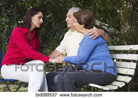 Stock Photo - Hispanic woman giving senior Hispanic couple bad news. Fotosearch