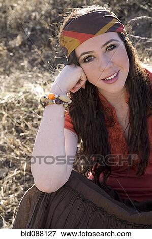Stock Photo - Hispanic woman in headscarf sitting on ground. Fotosearch