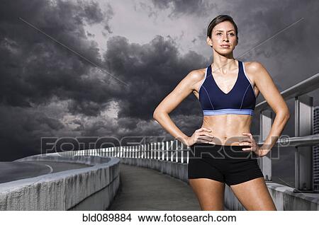 Picture - Hispanic woman in sportswear standing with hands on hips. Fotosearch