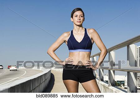 Stock Photography - Hispanic woman in sportswear standing with hands on hips. Fotosearch