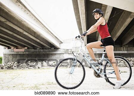 Hispanic woman riding bicycle in urban area View Large Photo Image Stock Image - Hispanic woman riding bicycle in urban area. Fotosearch