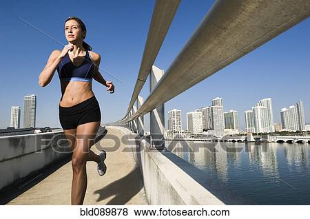 Stock Photo - Hispanic woman running near urban waterfront. Fotosearch