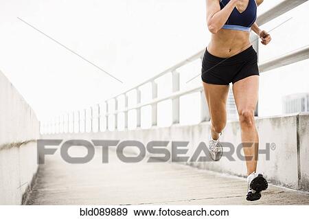 Stock Photo - Hispanic woman running on urban walkway. Fotosearch