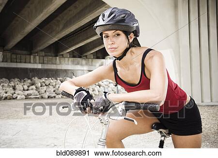 Hispanic woman sitting on bicycle in urban area View Large Photo Image Stock Image - Hispanic woman sitting on bicycle in urban area. Fotosearch