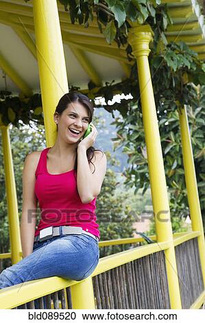 Hispanic woman sitting on porch talking on cell phone View Large Photo Image Stock Image - Hispanic woman sitting on porch talking on cell phone. Fotosearch